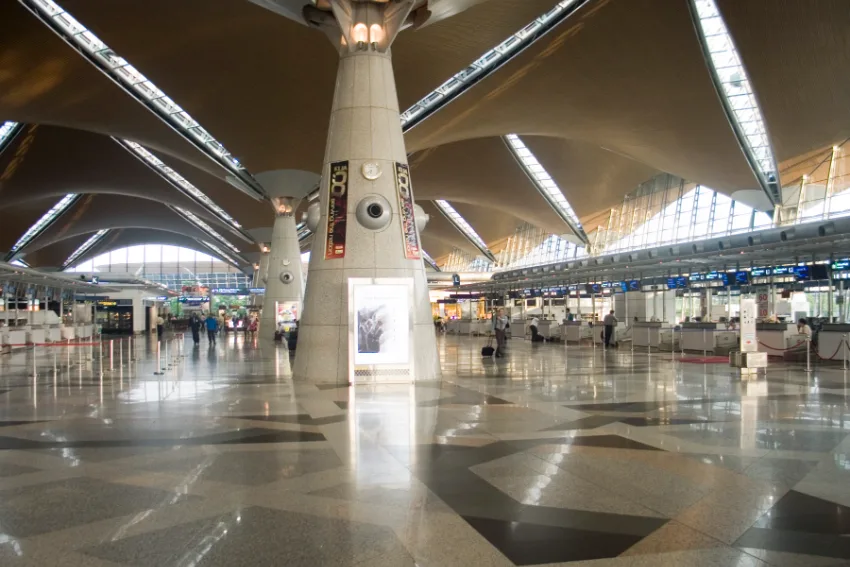 Dewan utama Lapangan Terbang Antarabangsa Kuala Lumpur (KLIA) dengan tiang dan bumbung berbentuk payung serta kaunter daftar masuk