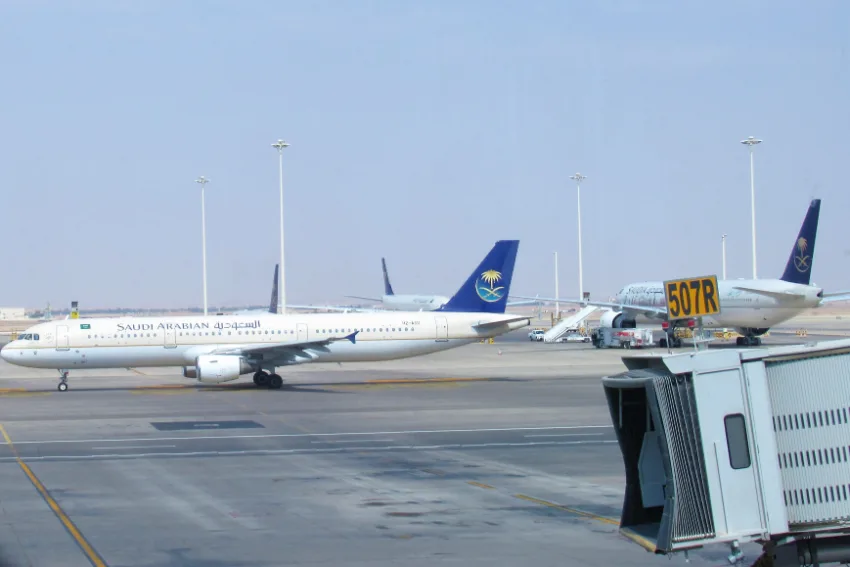Pesawat Saudia di apron Lapangan Terbang Antarabangsa King Khalid, Riyadh, dengan jambatan penumpang di sebelah kanan